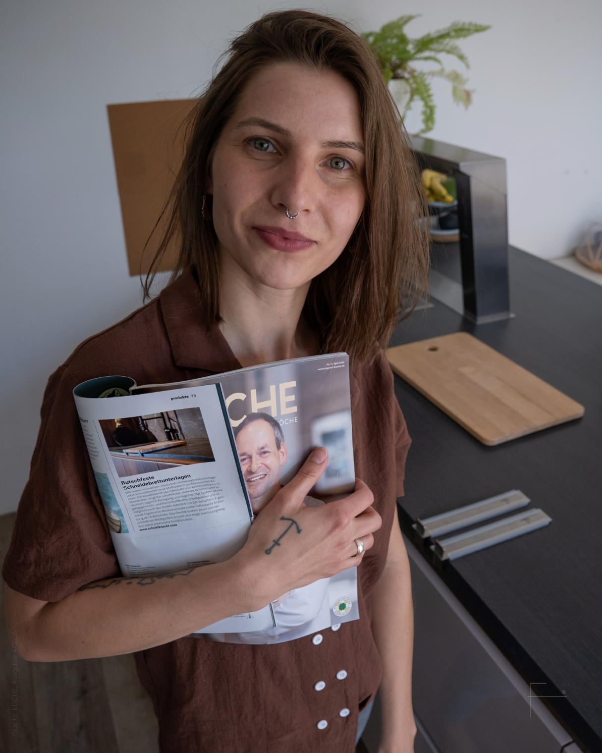 Gründerin Caroline Reiche in der Küche mit SchnittKnecht® und Fachmagazin KÜCHE (04/2026, Verband der Köche Deutschlands), das die Schneidebrettunterlage vorstellt