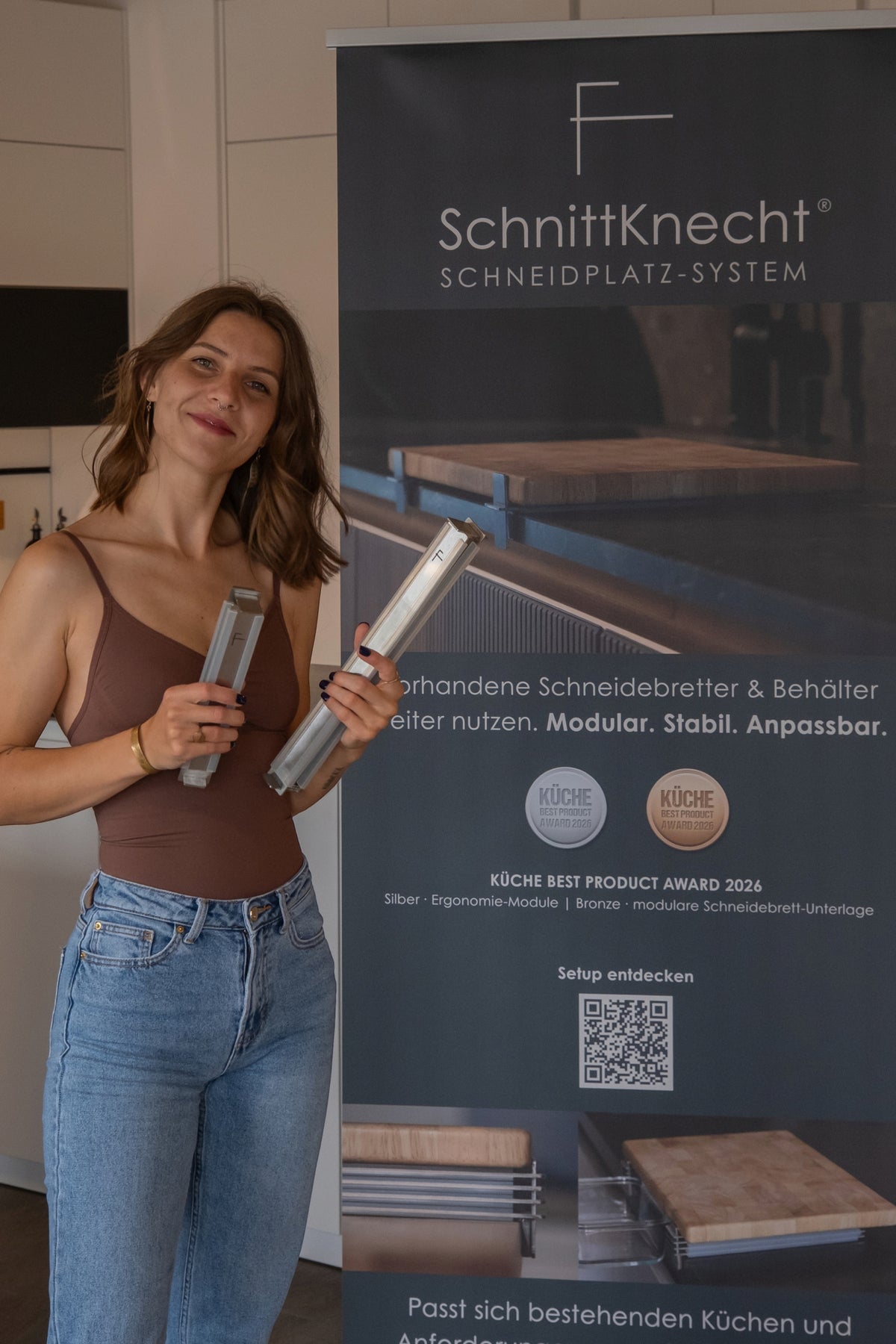 Caroline Reiche, Gründerin und Entwicklerin von SchnittKnecht®, mit dem modularen Schneidplatz-System vor einem SchnittKnecht®-Aufsteller.