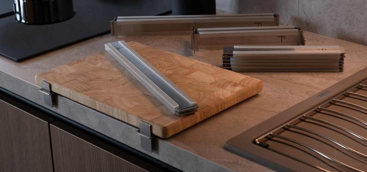 SchnittKnecht® Schneidebrett-Unterlage mit Holzschneidebrett und verschiedenen modularen Edelstahlkomponenten auf einer modernen Küchenarbeitsplatte.