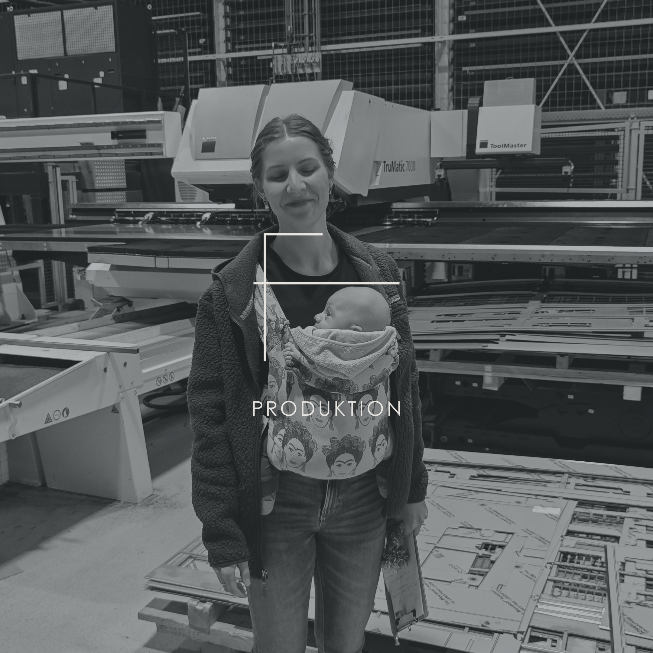Erfinderin, Entwicklerin und Geschäftsführerin (Founder) Caroline Reiche steht stolz in der regionalen Produktion des SchnittKnecht® in Bayern. Sie trägt ihren drei Monate alten Sohn Paul in einer Babytrage vor dem Bauch – Symbolbild für Familienunternehmen und ‚Designed & Made in Bavaria‘.