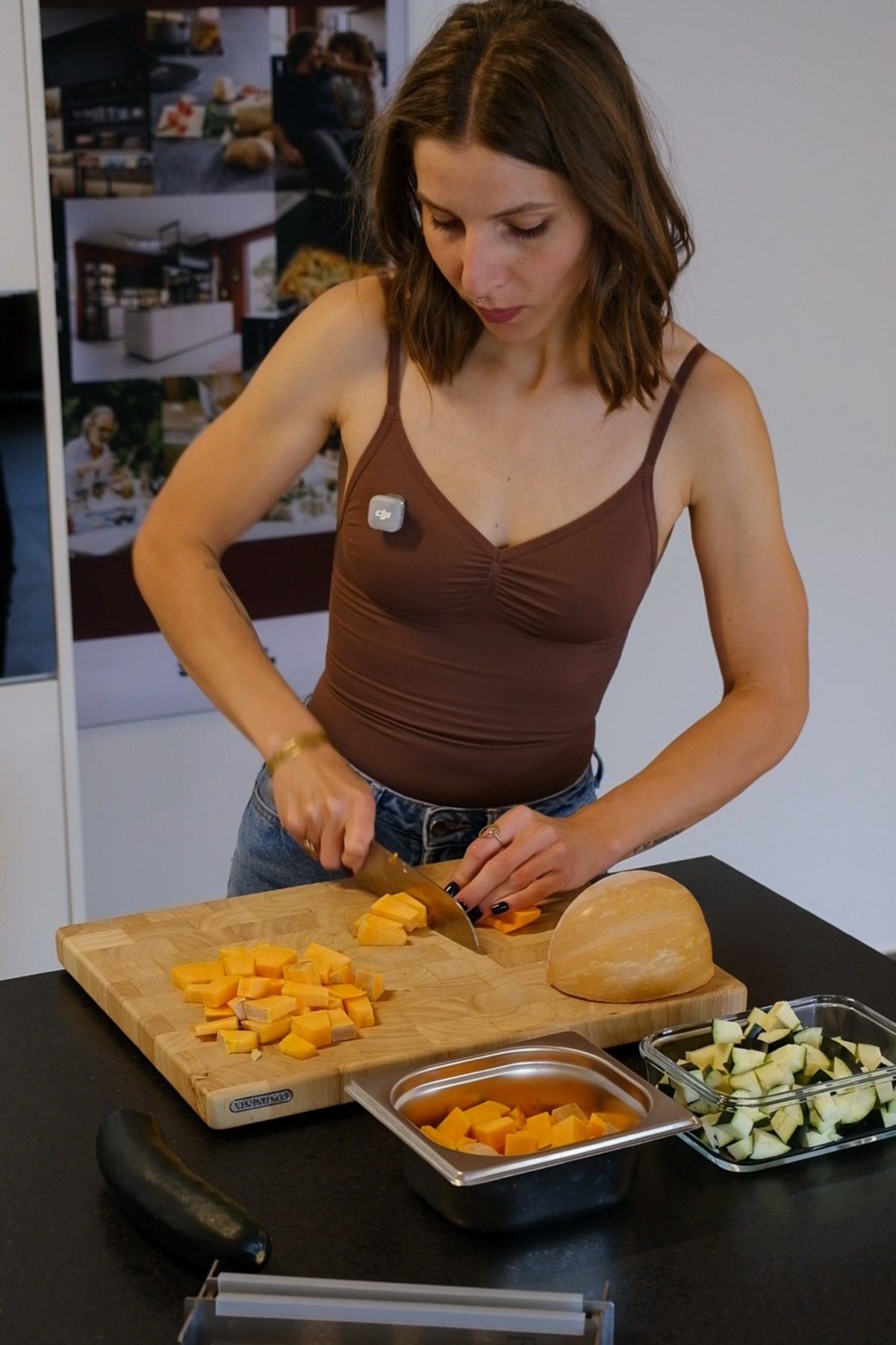 Caroline Reiche bereitet Kürbis auf einem Holzschneidebrett zu. Daneben stehen Glas- und Edelstahlbehälter mit geschnittenem Gemüse für die weitere Verarbeitung.