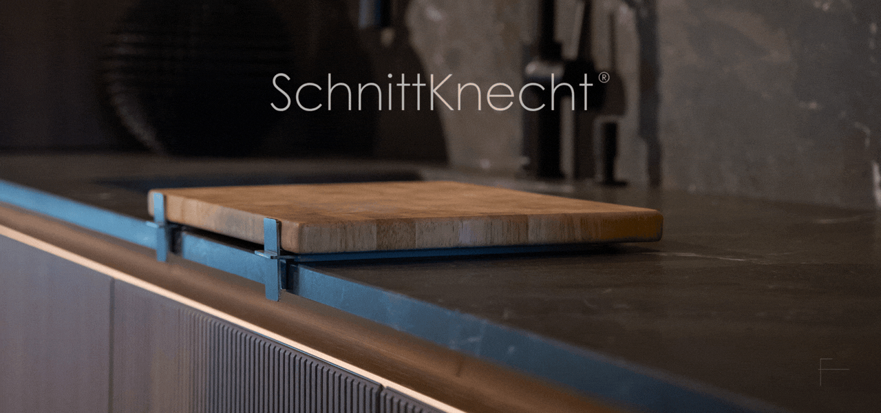 SchnittKnecht® Schneidebrett-Unterlage in moderner Küche mit Schneidebrett auf dunkler Arbeitsplatte. Das modulare System unterstützt sichere, rutschfeste und hygienische Schneidplätze.